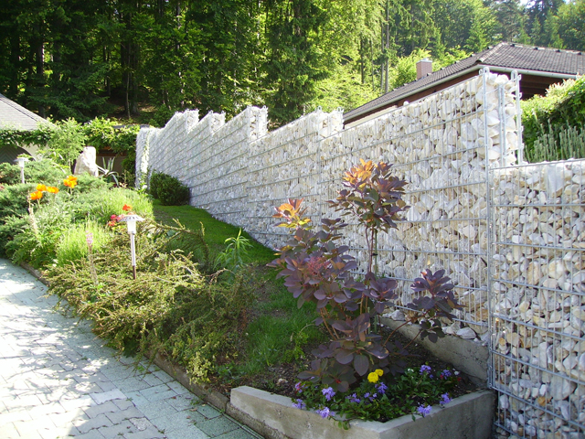 Kamena ograda Legi - Predstavlja vizuelnu i ujedno zvučnu barijeru, te ima jako široku primenu. Kombinacija sa manje primetnim žičanim  stubovima, ili jasnije naglašenim profilnim stubovima, rešetkastim panelom sa obe strane ograde i međusobnim povezivačima, čini čvrstu čeličnu konstrukciju, koja se ispunjava raznim vrstama i bojama kamena, formirajući izgled kamenog zida a bez potrebe za zidanjem. Kamena ograda se proizvodi u visinama 630-2430mm. Kombinuje se sa RM, R-S i ukrasnim panelima.